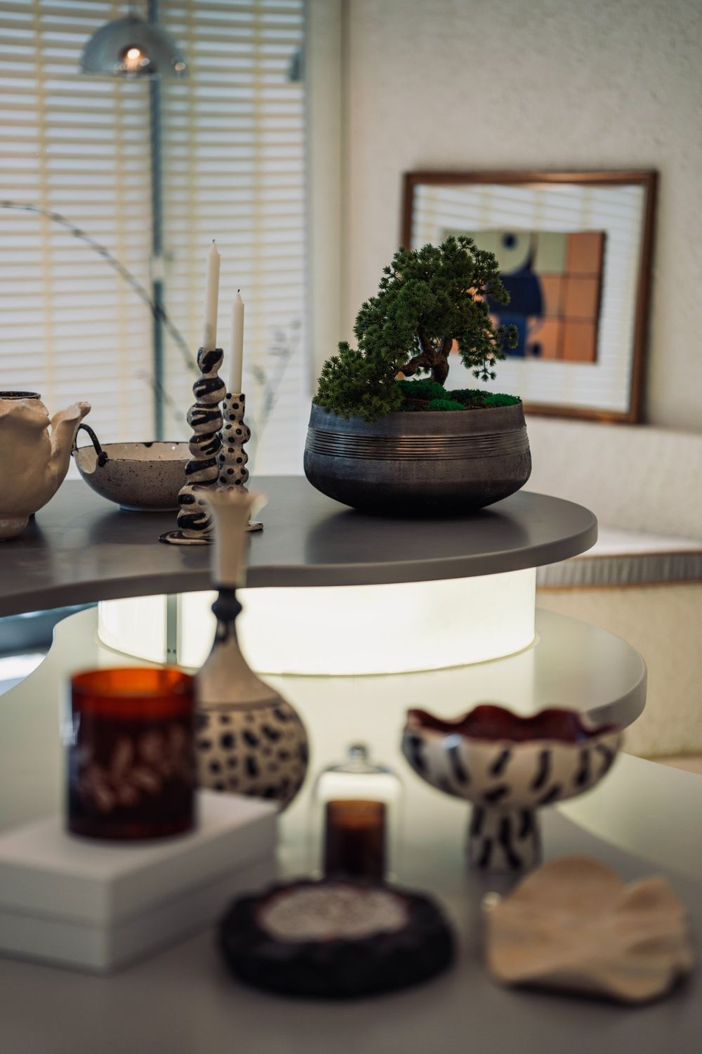 Fasulye Masa üzerinde bonsai ve seramik objeler; arkada çerçeveli karo çalışması